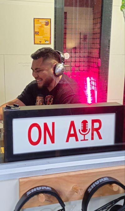 Artist Lewis T. in a booth with a sign that says On Air