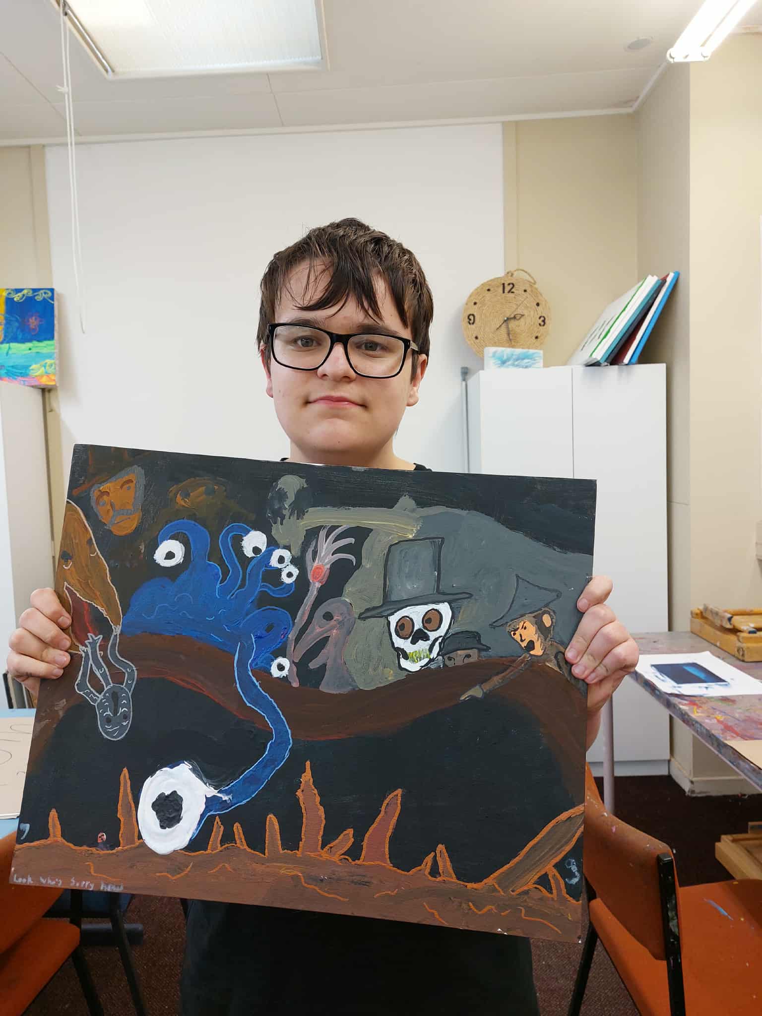 Artist Oscar holding one of his colourful paintings 